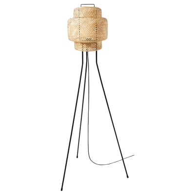 A SINNERLIG floor lamp with a bamboo shade. The lamp has a unique weaved design and stands on three black legs. It is beige in colour.