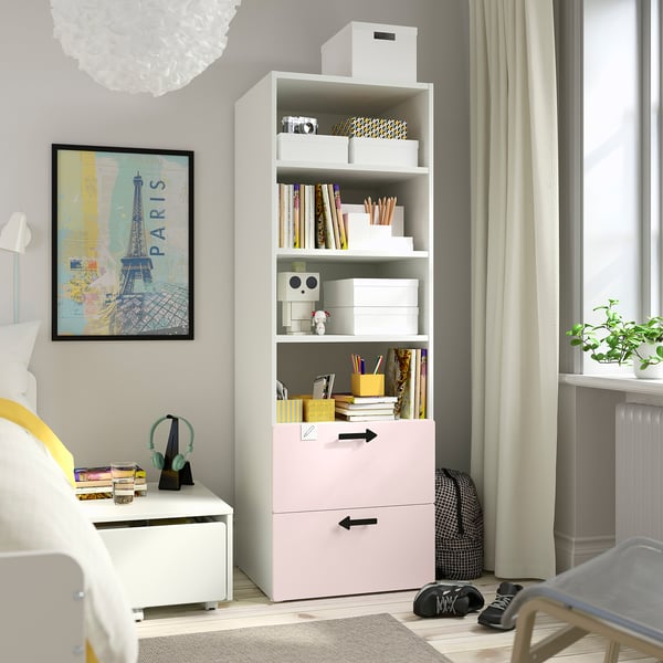 Bright kids room with pink SMÅSTAD bookcase & drawers. Storage unit holds books, toys, and stationery. Near window and bed, fitting well in corner.