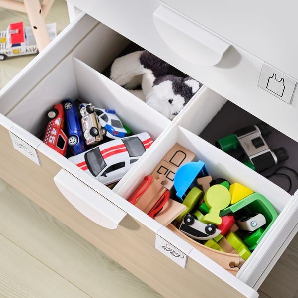Open white toy chest with compartments filled with colourful toys and stuffed animals.