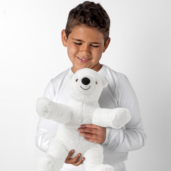 Boy holding a white SNUTTIG teddy bear, smiling.