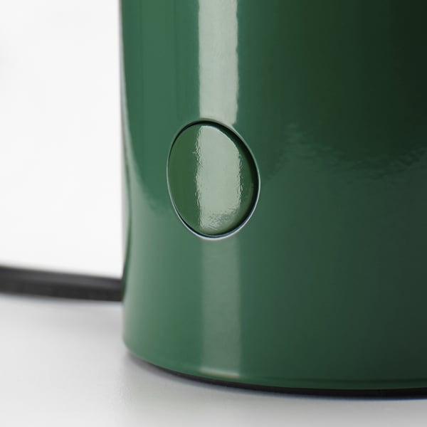 Green table lamp with sleek design, round button on side, shiny surface.