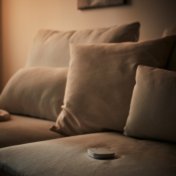 Beige, rectangular remote on grey couch cushion.