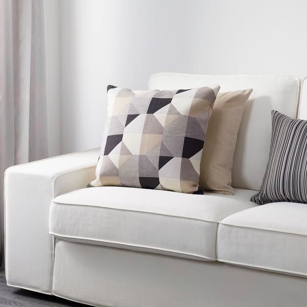 A white sofa with colourful geometric cushions, including a large square one.