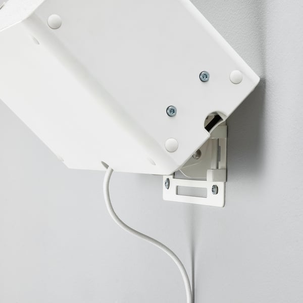 White wall-mount bracket for speaker, securely fixed with screws, connected by a cable.
