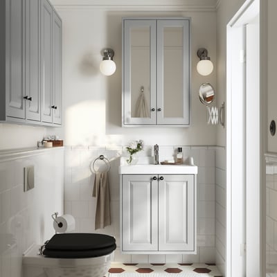 Modern bathroom with grey TÄNNFORSEN vanity, sink, mirrors, storage, white tiles, toilet, and tub.