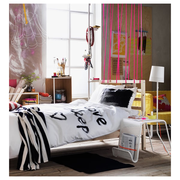 Bright, artistic bedroom with white TARVA bed, bold prints, and colourful decor.
