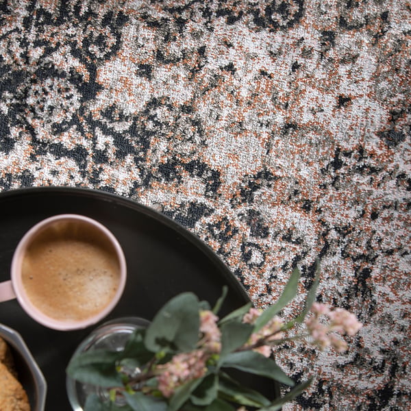A cosy scene with a mug of coffee and fresh flowers on a stylish, durable rug.