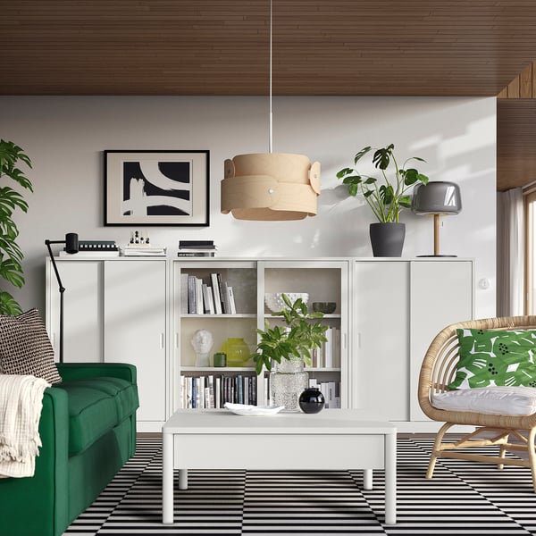 Stylish modern living room with green sofa, white TONSTAD cabinets, striped rug, and wooden pendant light.