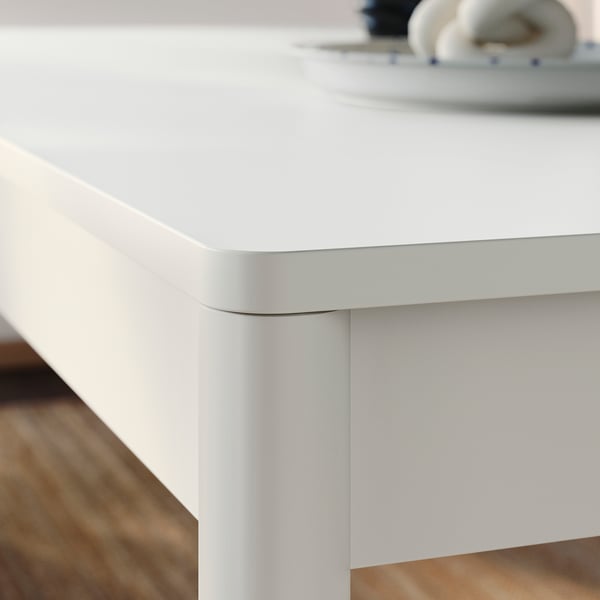 Close-up of clean-lined, modern table with smooth, rounded edges and sturdy, painted wood legs.