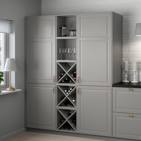 A large grey TORNVIKEN kitchen cabinet with wine storage, featuring glass doors, holding bottles and wine glasses, next to a counter with decor.