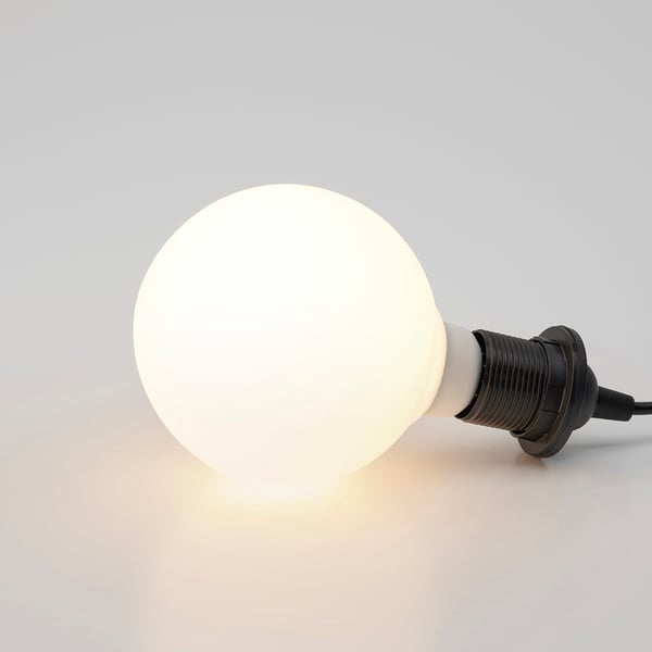 A frosted glass bulb emits warm, diffused light from its black base, creating a cosy ambiance.