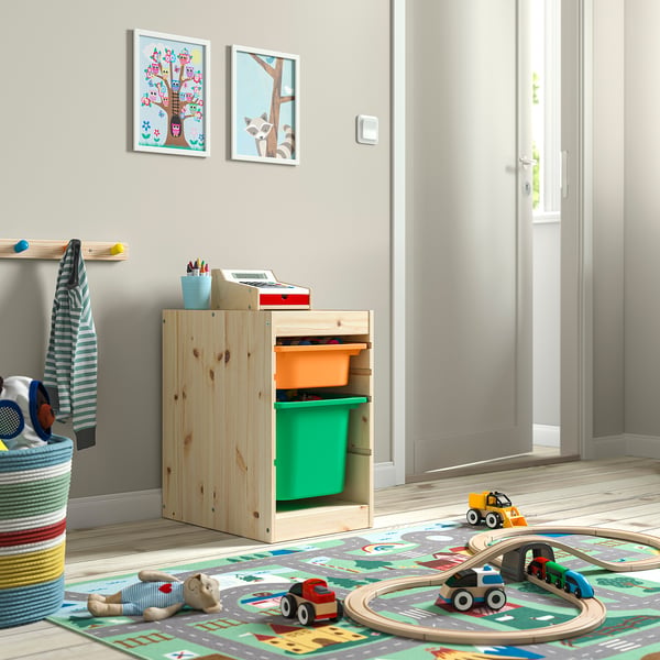 Childs play area with wooden TROFAST storage unit, bright green bins, toys, and colourful rug.