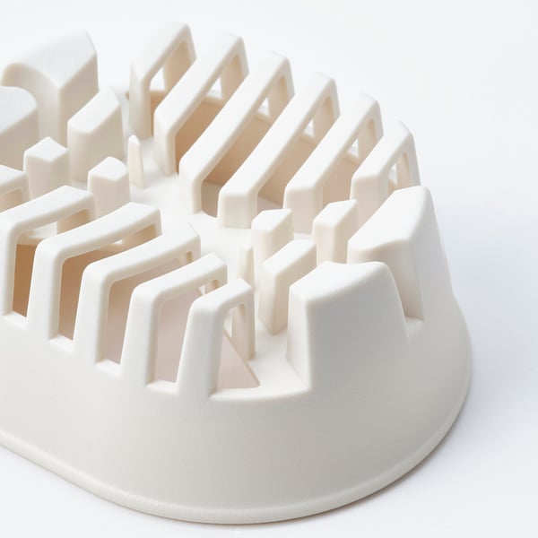 White plastic kitchen tool with multiple slots, designed for slicing and holding items.