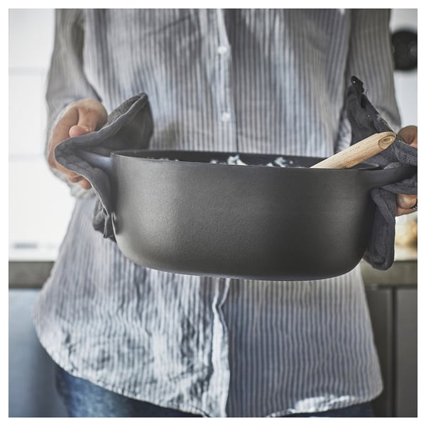Person holding black VARDAGEN enamel cast iron pan.