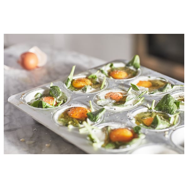Silver muffin tin with six compartments filled with spinach and cherry tomatoes ready for baking. High quality anodized aluminium.