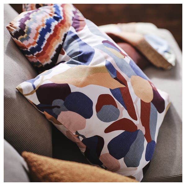 Colourful throw pillows on couch, abstract shapes and patterns in earth tones, soft decorative cushions.