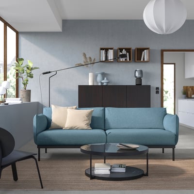 Modernes Wohnzimmer mit blaugrünem ÄPPLARYD-Sofa, schwarzem Couchtisch und minimalistischem Dekor.
