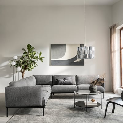 Modernes Wohnzimmer mit grauem ÄPPLARYD-Sofa, abstrakter Kunst, Pendelleuchte, rundem Couchtisch und großem Fenster mit beigen Vorhängen.