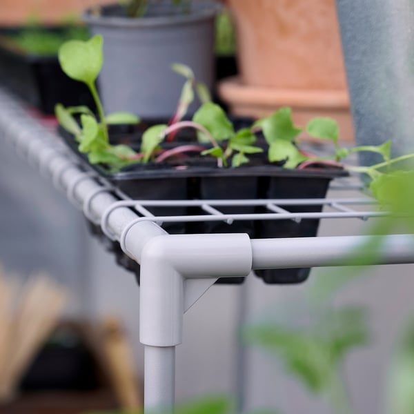 Kleine weiße Gewächshausregale bieten Platz für grüne Pflanztöpfe und fördern so den Indoor-Gartenbau.