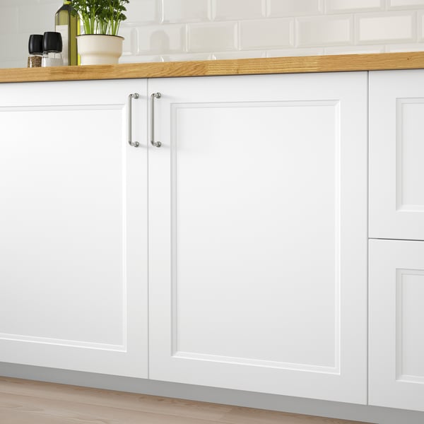 Weißer Küchenschrank mit Holzarbeitsplatte. Weiche Linien und ein zeitloses Design. Zu sehen sind zwei Türen mit Metallgriffen.