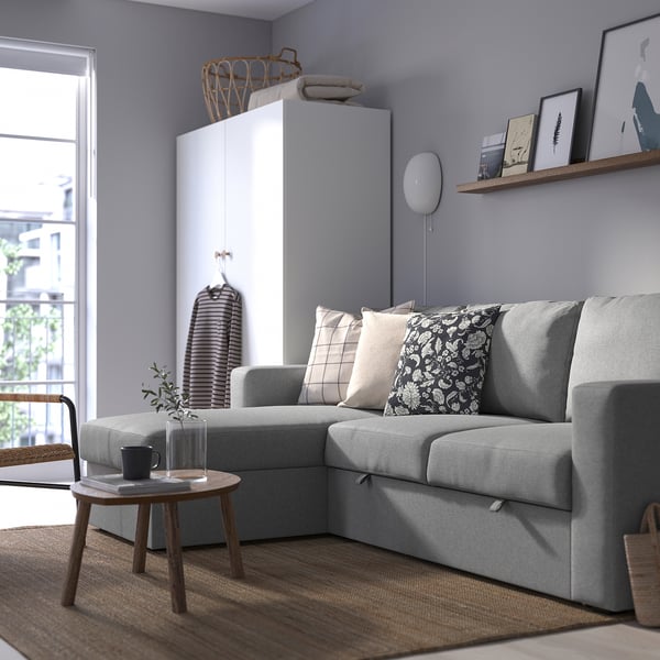 Graues Schlafsofa mit großen Kissen, schickes Design, umgeben von Holzmöbeln.
