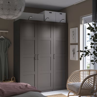 Moderner grauer Hochschrank mit zwei Türen, Korbstuhl, Landschaftsfenster, Kunst, Leuchte.