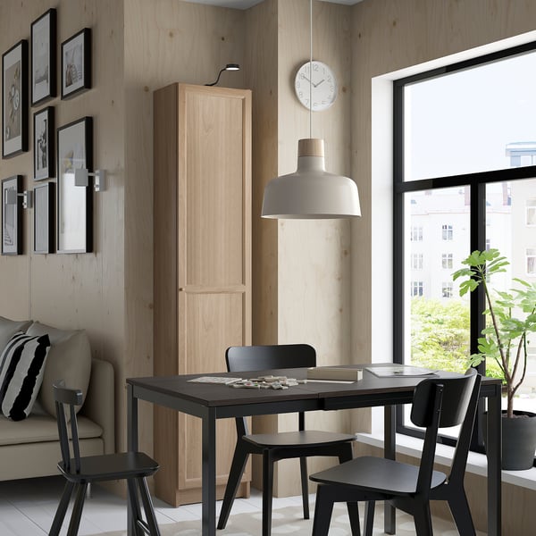 Modernes Wohnzimmer mit Esstisch, Stühlen, Bücherregal, Sofa, Uhr und Lampe.