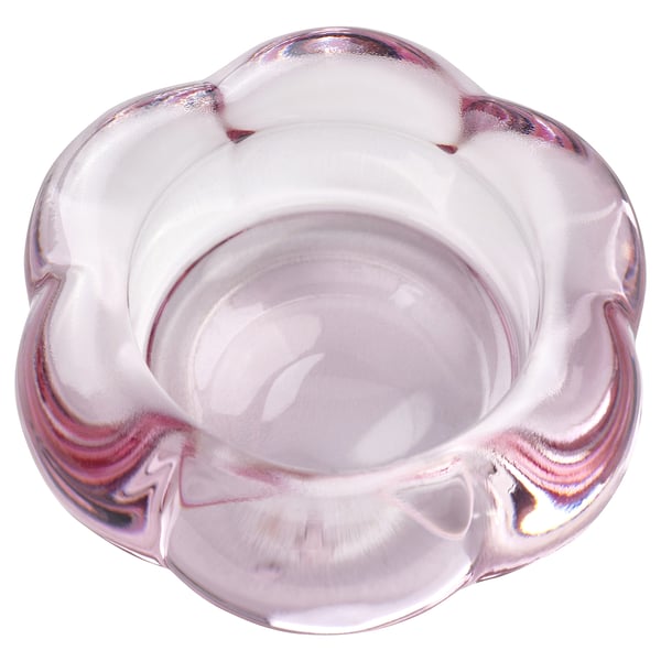 Ein Teelichthalter aus klarem, rosafarbenem Glas namens BLADFÅGEL, inspiriert von einer Blumenform, mit einem modernen Design.
