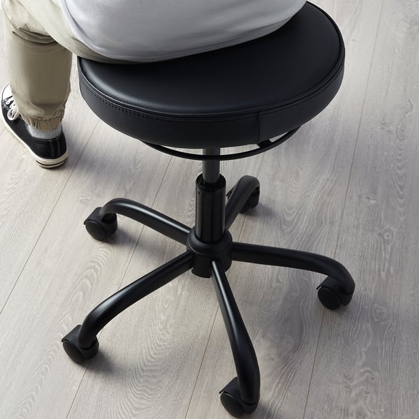 Sitzperson auf aktivem Hocker BLYKOBB mit Ledersitz, Fünf-Stern-Gestell und Rädern.