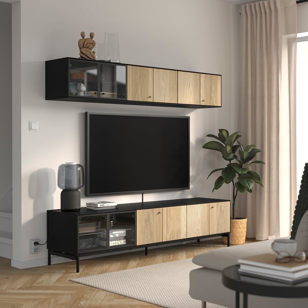 Modernes Wohnzimmer mit BOASTAD TV-Bank und Regal, hellgrauer Wand, beigen Vorhängen, Topfpflanze und grauen Möbeln.