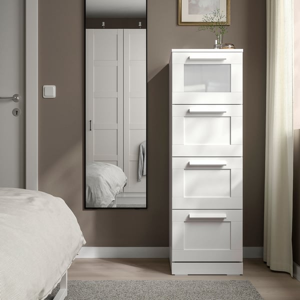 Moderne weiße BRIMNES-Truhe, großes, schlankes Design mit Glasplatte, steht neben dem Bett, neben dem Schrank.