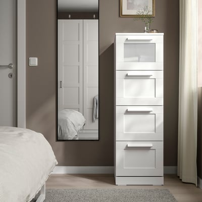 Moderne weiße BRIMNES-Truhe, großes, schlankes Design mit Glasplatte, steht neben dem Bett, neben dem Schrank.
