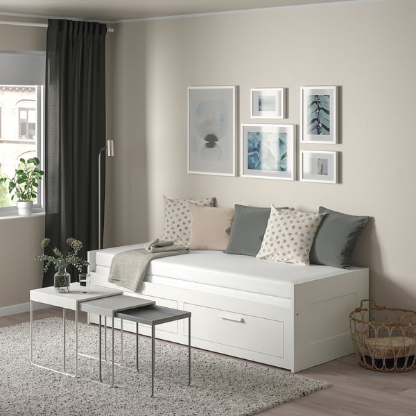 Minimalistisches Wohnzimmer mit BRIMNES-Möbeln , abstrakter Kunst, grauen Vorhängen, Kissen und einer Pflanze.