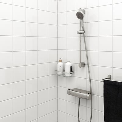 BROGRUND Duschsystem in Chromoptik, Steigrohr, Handbrause, schwarzes Handtuch, Toilettenablage in weiß gefliester Dusche.