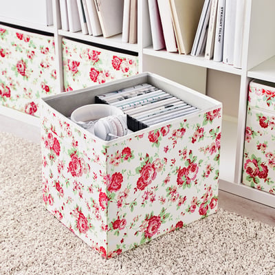 Blumen-Aufbewahrungsbox auf dem Regal mit Kopfhörern und Kabeln, Teil der Kallax-Einheit.