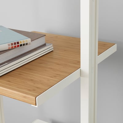 Eine Nahaufnahme eines Bambusregals auf einem weißen Metallrahmen, in dem mehrere Bücher stehen.