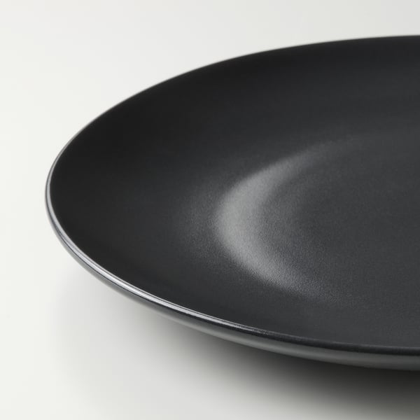 Platte aus schwarzem Feinsteinzeug mit glatter, glänzender Oberfläche und abgerundeten Kanten. Elegantes, schlichtes Design, perfekt für verschiedene Mahlzeiten.