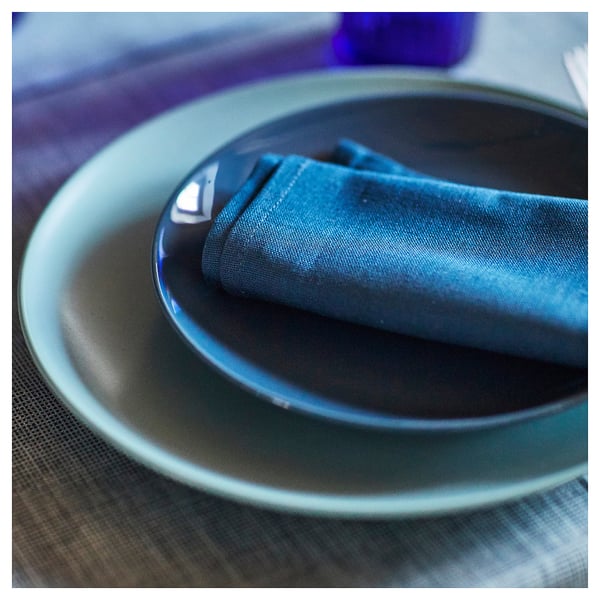Teller aus blau glasiertem Steinzeug mit Serviette. Einfaches, rundes Design. Bereit für die Tischdekoration.