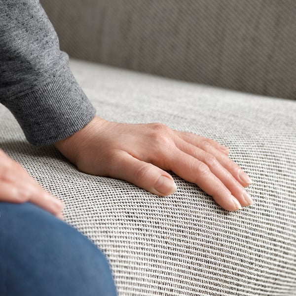 Hände auf grauen FAMMARP Sofas strukturierter Stoff.