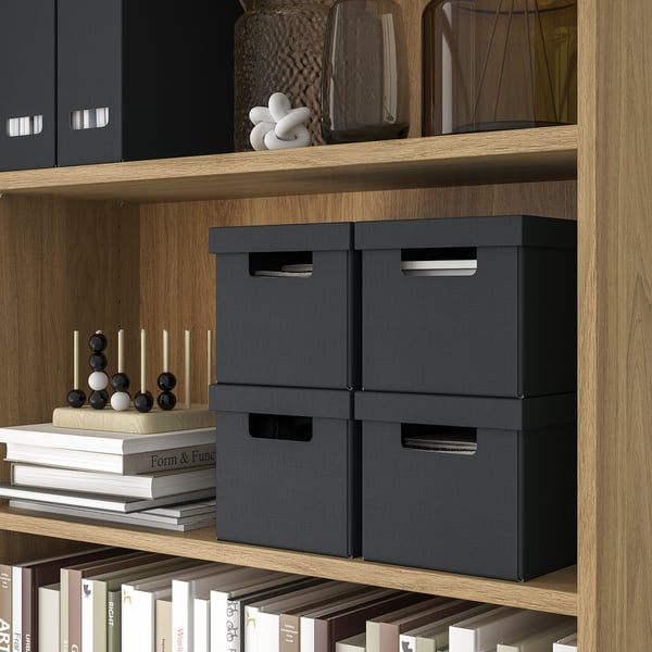 Holzregale mit schwarzen Aufbewahrungsboxen, Dekorationsartikeln und Büchern. Boxen, ideal für kleines Zubehör, Fotos und Kabel.