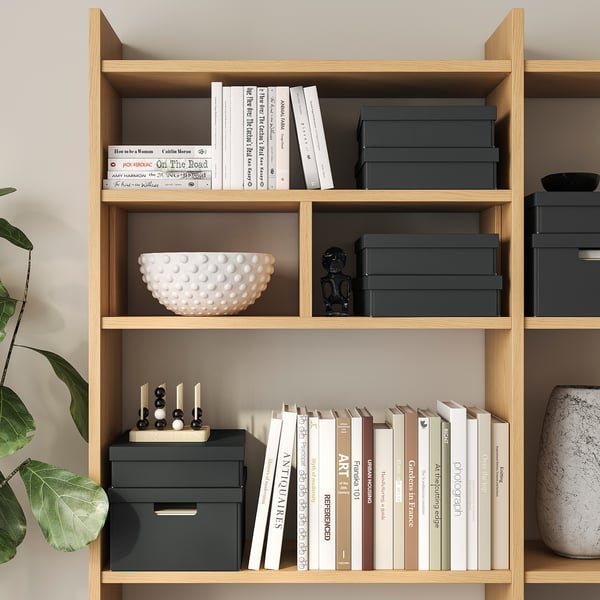 Bücherregal mit Büchern, Dekoration und Stauraum. Schwarze Figur und weiße Schale.