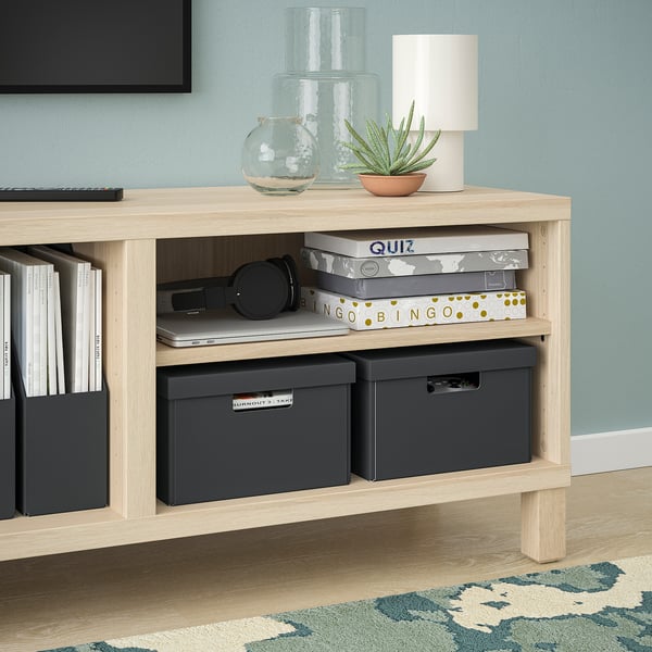 Leichtes Aufbewahrungsregal aus Holz mit schwarzen Boxen, Büchern, Lampe, Pflanze und Kopfhörern, ideal zum Organisieren und Dekorieren.