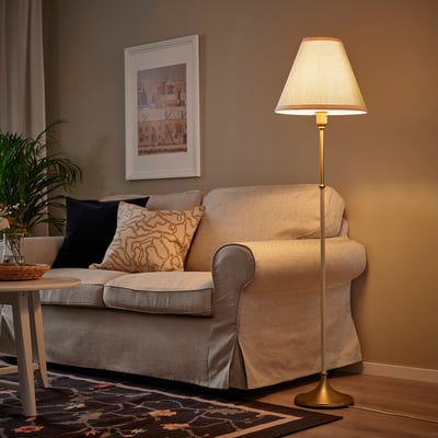 Modernes Wohnzimmer mit FLYGHÖJD-Lampe, beigem Sofa, Pflanze und Wandkunst.