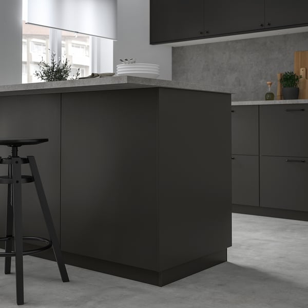 Moderne schwarze Kücheninsel mit schlanker Arbeitsplatte, kleiner als benachbarte Schränke, bietet Platz für Teller und Pflanzen.