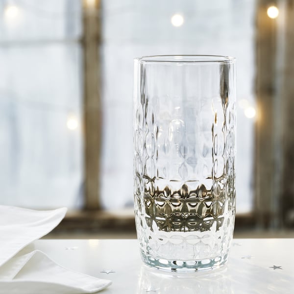 Eleganter Glasbecher mit Facetten, Tuch und Konfetti.