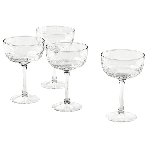 Vier Champagner-Coupes mit facettiertem Design und langen Stielen.