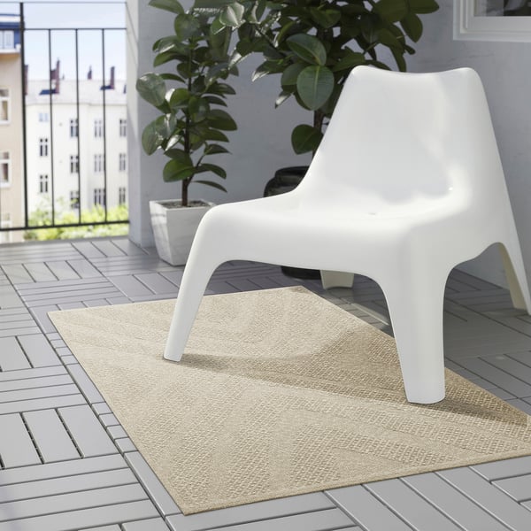 Moderne Terrasse mit beigem Teppich, weißem Stuhl und großer grüner Pflanze.