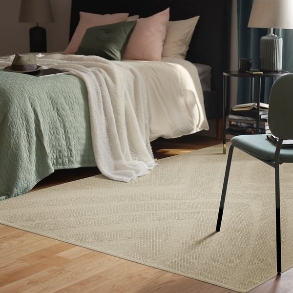 Ruhiges Schlafzimmer mit FULLMAKT beigem Teppich, Stuhl, Bett und Dekor. Teppich größer als Stuhl, passt gut in den Raum.