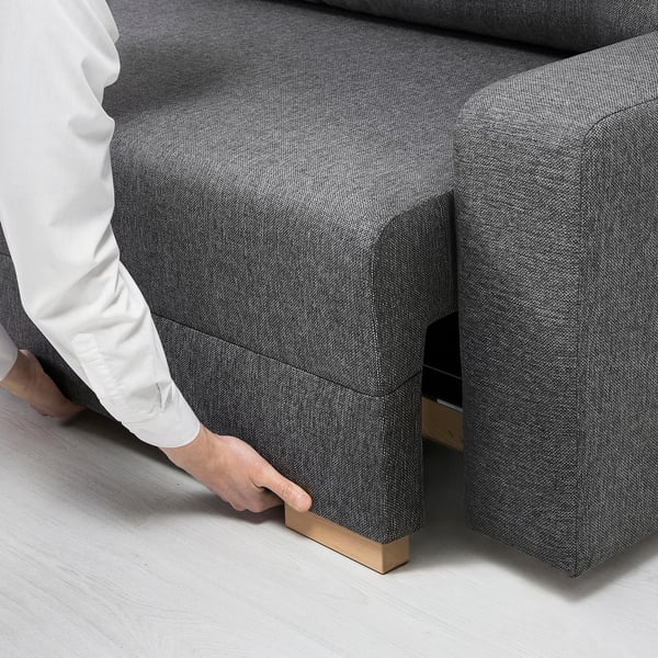 Person stellt Schlafsofa mit Stauraum darunter ein.