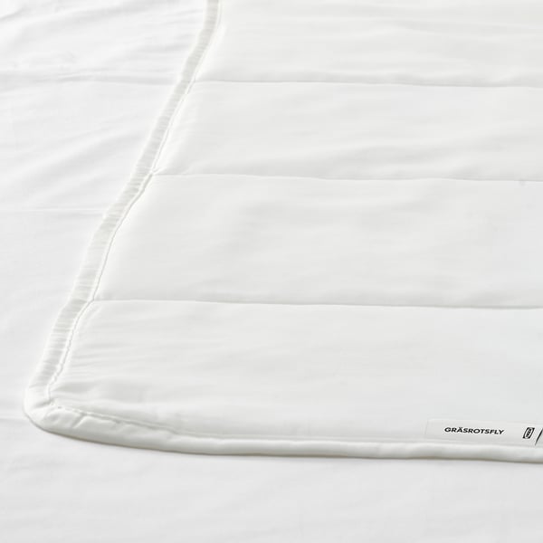 Nahaufnahme einer weißen Bettdecke mit glatten Nähten und GRÄSROTSFLY-Etikett.